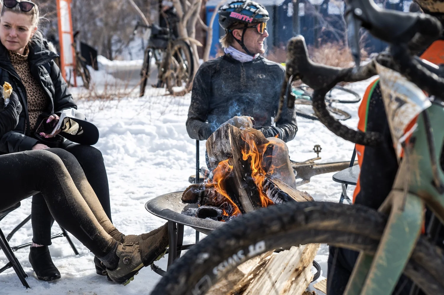 Old Man Winter participants warming beside a fire in the snow
